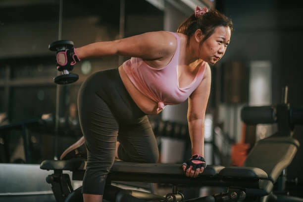 woman holding a dumbbell and leaning on a bench