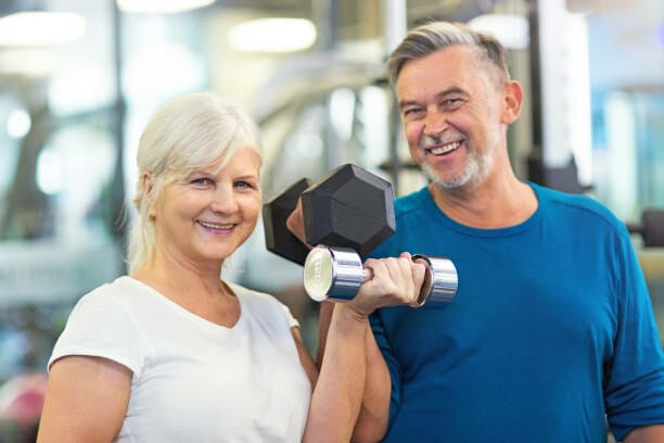 Building Strength After 40: Yes, You Can! 1 40+ man and woman lifting weights in the gym using dumbbells to gain strength