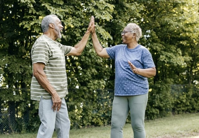 active older couple giving a high five to each other outdoors