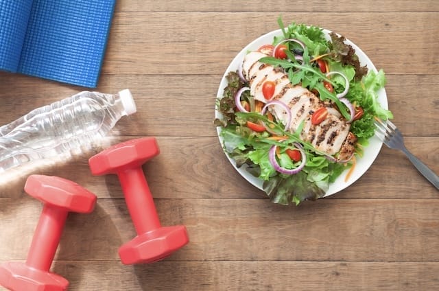 Water, Light Dumbbells, Yoga Mat, and Salad with Chicken as part of Weight Loss Journey