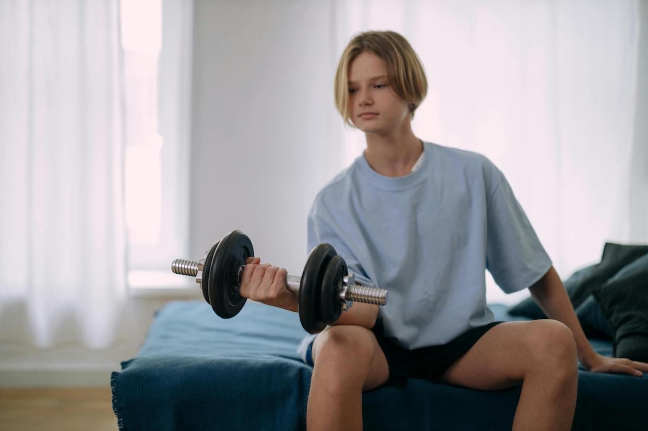 teen lifting dumbbells in his bedroom